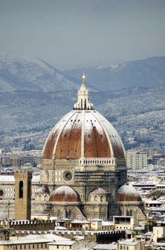 an aerial view of the dome of a building with mountains in the backgroud