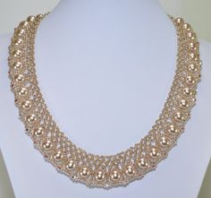 a gold necklace with pearls is displayed on a white mannequins neckline