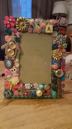 a wooden table topped with a frame covered in lots of different types of buttons and beads