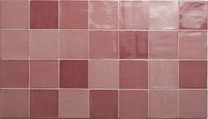 a pink tile wall with different shades of red and white tiles on the bottom half