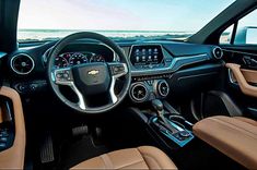 the interior of a car with dashboard, steering wheel and center console in front of an ocean view