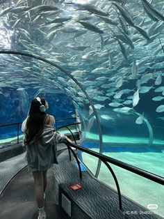 a woman is looking at fish in an aquarium