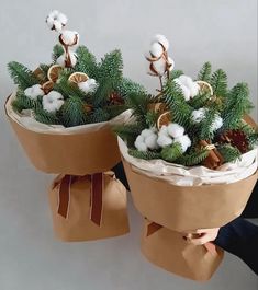 two brown paper bags with white flowers and pine cones on them, tied to each other