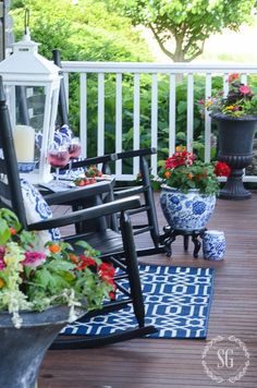 a porch with chairs and potted plants on the back deck, along with an area rug