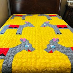 a bed with a yellow and gray bedspread that has an abstract design on it