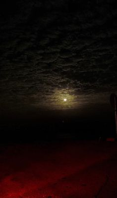 the full moon is seen in the night sky over an empty field with red lights