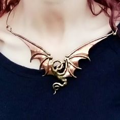 a woman with red hair wearing a gold dragon necklace