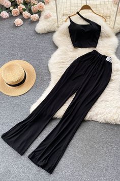 two pieces of black clothing sitting on top of a white rug next to a straw hat