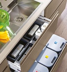 an open drawer in a kitchen filled with containers and bottles on top of a wooden floor