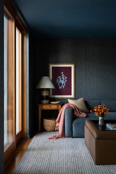 a living room filled with furniture and a painting hanging on the wall next to a window