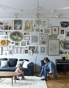 there are many pictures on the wall in this room and one man is sitting down