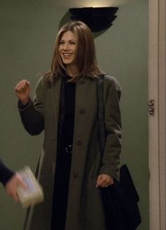 a woman standing in front of a door with her hand up to the camera and smiling