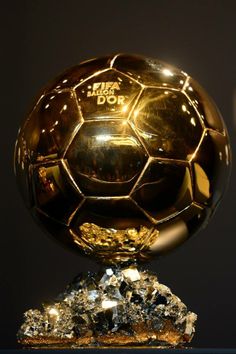 a golden soccer ball sitting on top of a metal base with gold foil around it