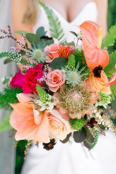 a bride holding a bouquet of flowers and greenery