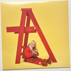 a woman sitting on the ground in front of a red wooden structure with her legs crossed