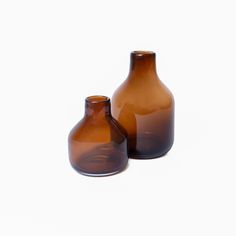 two brown vases sitting next to each other on a white surface with no one around them