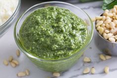 a glass bowl filled with green pesto next to other ingredients