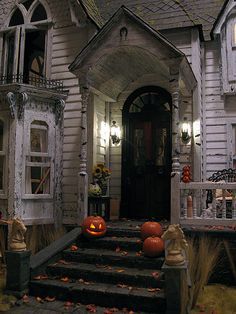 a house decorated for halloween with pumpkins on the steps