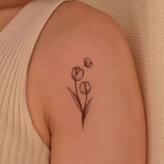 a woman's arm with a small tattoo of three tulips on it