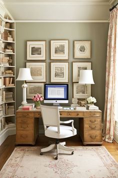 a desk with a computer on top of it in front of bookshelves and pictures