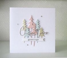 a white card with trees and the words christmas greetings written in silver on it