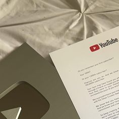 an open youtube box sitting on top of a bed next to a piece of paper