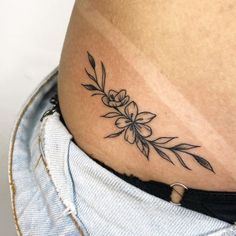 a woman's stomach with a flower tattoo on the side of her belly,