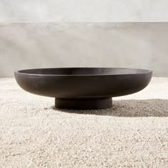 a large black bowl sitting on top of a white floor next to a cement wall