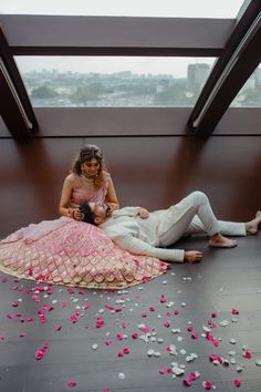 a man and woman laying on the floor next to each other with petals all over them