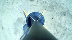 an aerial view of a yellow and blue cone on the ground next to a metal pipe