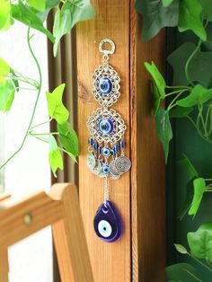 an evil eye charm hanging from a wooden door next to a green leafy plant