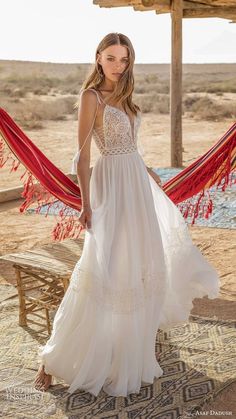 a woman in a white wedding dress standing on a rug with red tassels