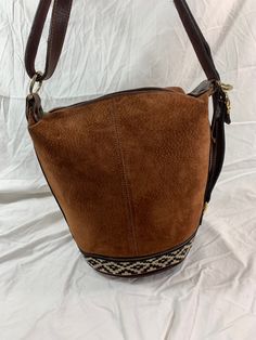 "Measurements are 12\" top wide, 11\"5 high and 9\" deep with one 35\" shoulder strap at its longest with a 10\" drop. There is one large main compartment, lined in beige fabric, back wall zipper pocket and a top zipper closure. This lovely bag is made of brown leather with tan pigskin suede, light stitching and gold tone hardware. Bag is vintage and there are light scuffs on the exterior and there are no tears. There is one exterior zipper pocket for easy to access items. ---------------------- Brown Leather Bucket Bag With Large Capacity, Vintage Large Capacity Crossbody Bucket Bag, Beige Leather Bucket Satchel, Large Capacity Brown Leather Bucket Bag, Leather Trim Bucket Satchel, Brown Leather Handles Bucket Bag Tote, Brown Leather Handled Bucket Bag Tote, Brown Leather Handle Bucket Bag Tote, Everyday Bucket Satchel With Leather Trim