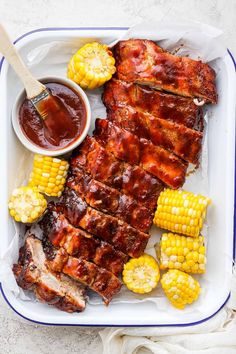 bbq ribs and corn on the cob with barbecue sauce in a white tray