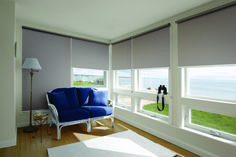 a living room filled with furniture and windows covered in roller shades on top of them