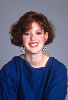 a woman with red hair smiling and wearing earrings