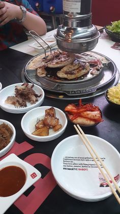 a table topped with plates and bowls filled with food next to chopsticks on top of a plate