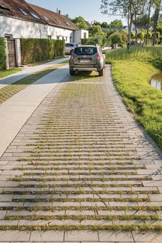 a car parked on the side of a road next to a grass covered sidewalk and water