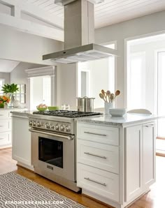 a white kitchen with an oven, stove and counter top in the middle of it