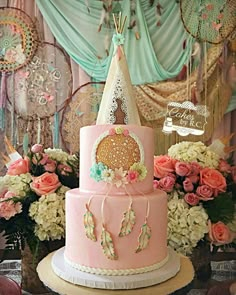 a three tiered pink cake sitting on top of a table next to some flowers