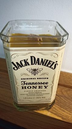 a jar of jack daniels honey sitting on top of a wooden table next to a wall