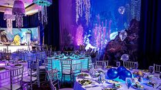 a room filled with tables and chairs covered in purple lights