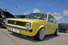 a yellow car parked next to other cars in a parking lot