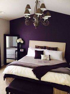 a large bed sitting under a chandelier next to a purple and white wall