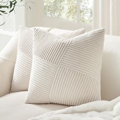 two white pillows sitting on top of a couch next to a vase filled with flowers