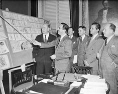 a group of men standing next to each other in front of a whiteboard with pictures on it