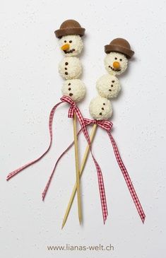 two snowmen made out of marshmallows on sticks