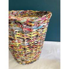 a basket made out of magazines sitting on top of a white table next to a blue wall