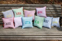 six embroidered pillows sitting on top of a wooden bench