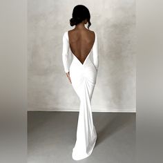 the back of a woman's white dress is shown in this image, with her hands on her hips